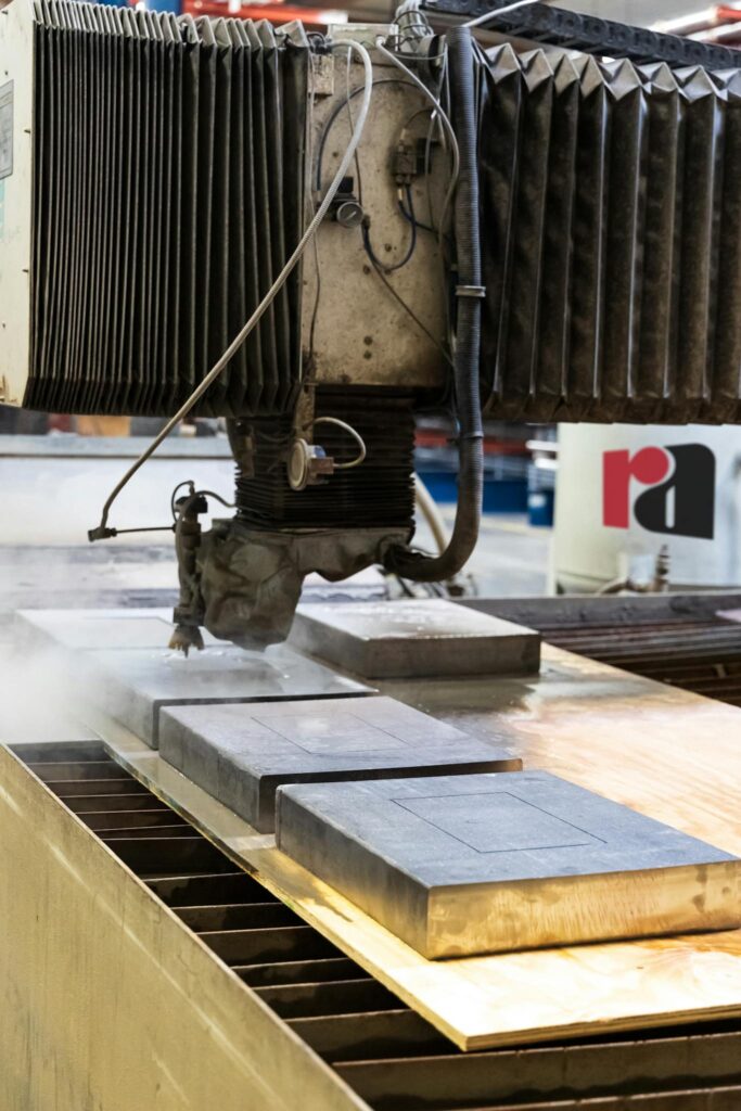 Close-up of a water jet cutting machine slicing through metal in a factory setting.