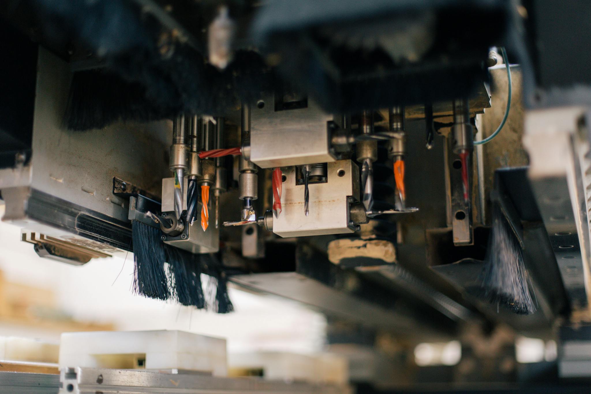 Detailed view of an industrial machine with multiple drills and brushes in a factory setting.