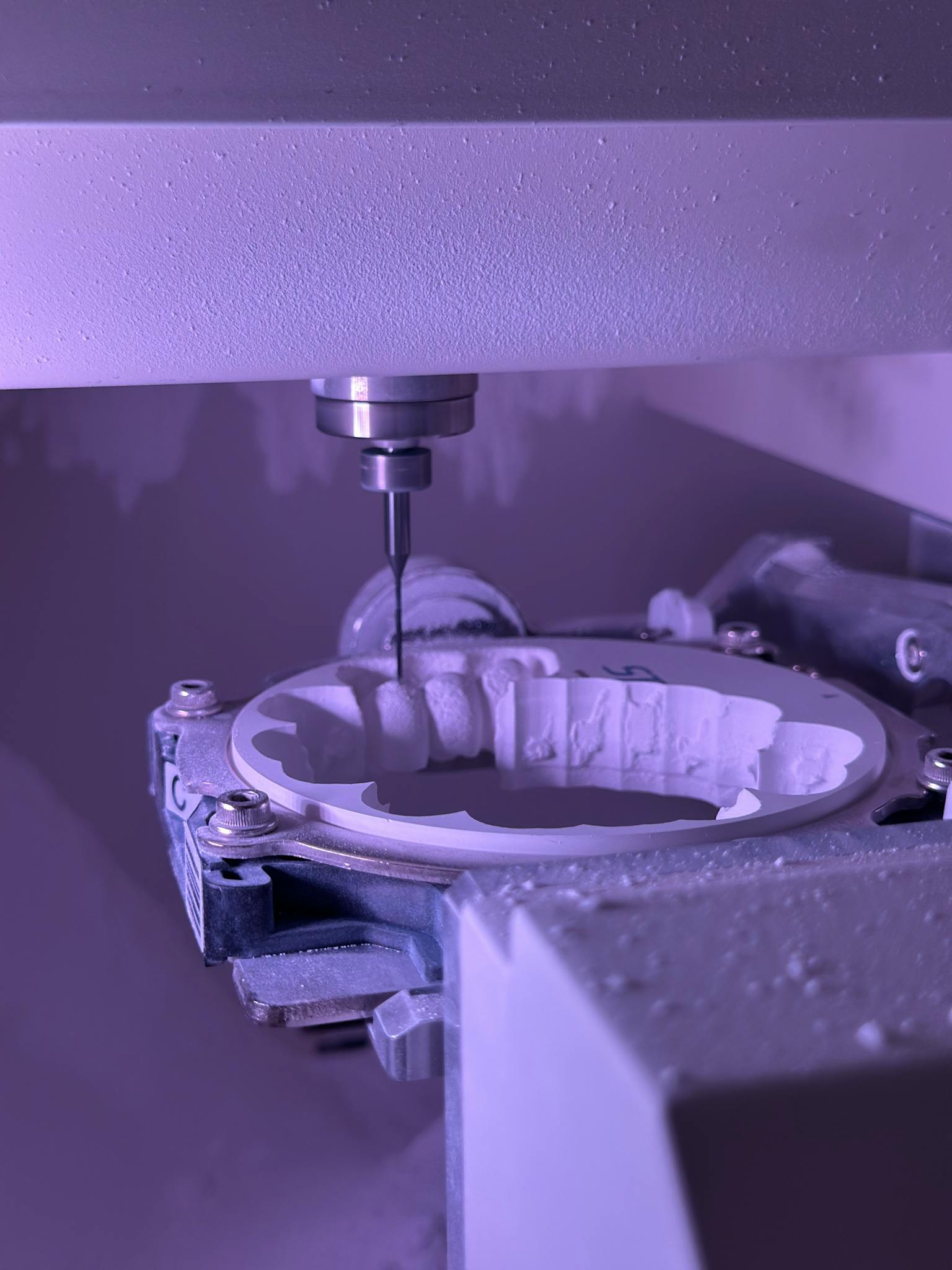 Detailed view of CNC machine milling process with purple lighting, highlighting precision engineering.